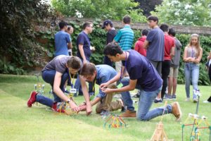 Students at Reach Cambridge engage in a creative engineering project outdoors, fostering innovation and teamwork.